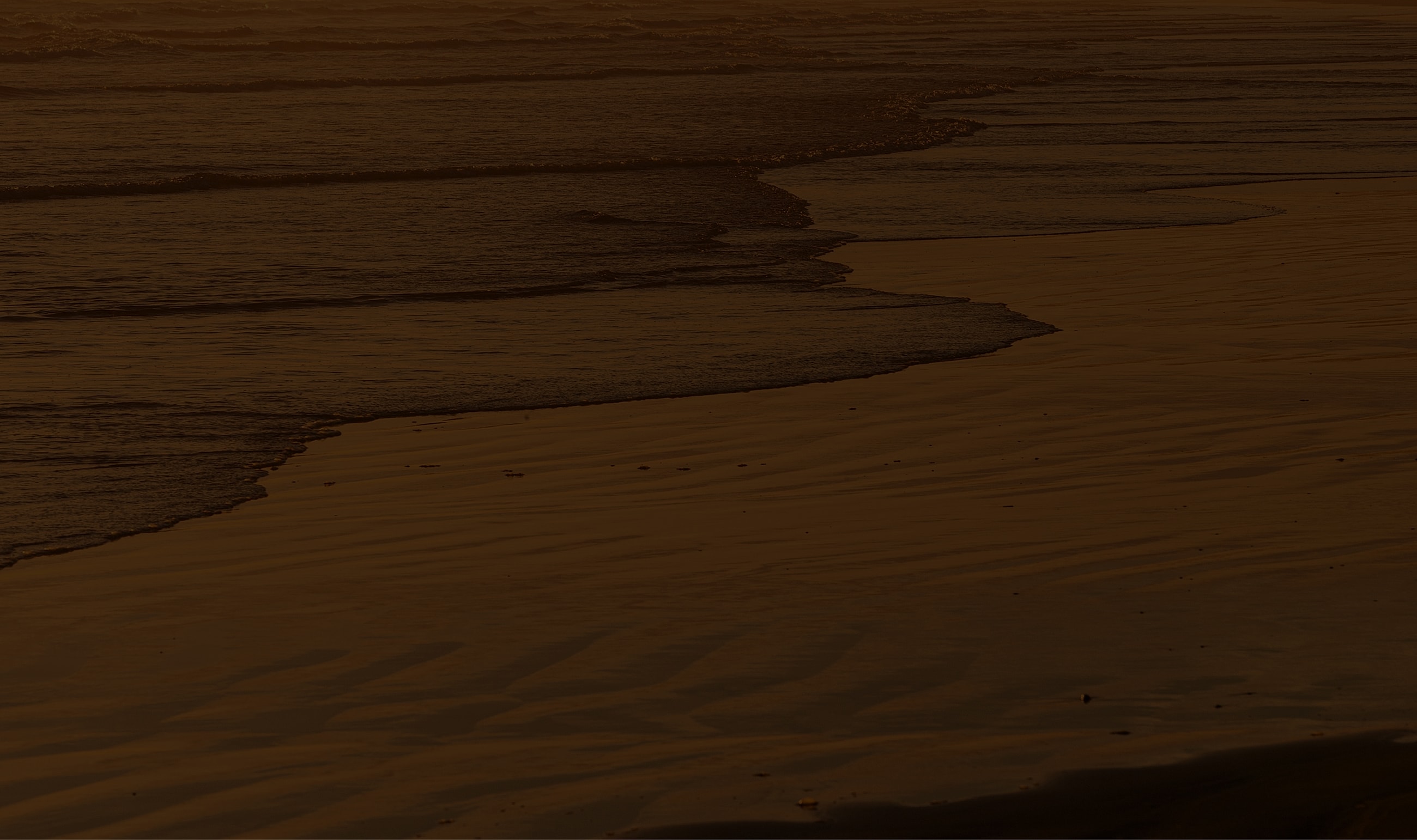 Serene beach at sunset with gentle waves.