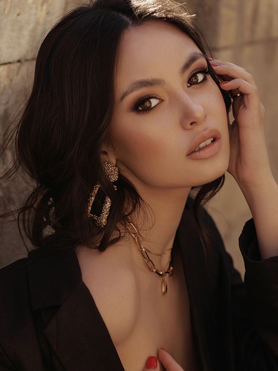 Woman with elegant jewelry, posing thoughtfully.