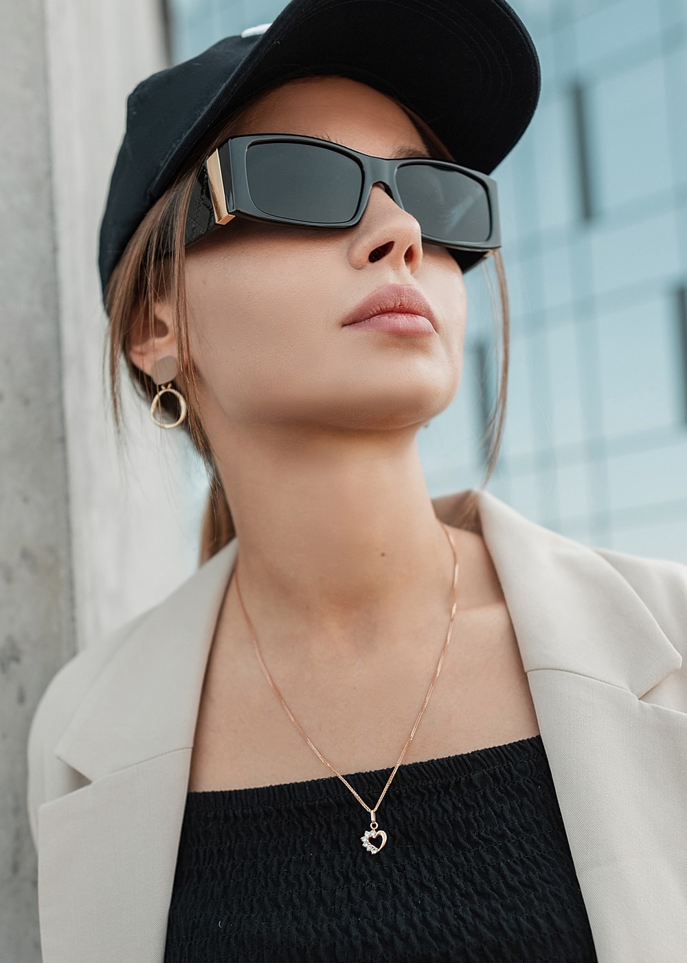 Fashionable woman in sunglasses and cap outdoors.