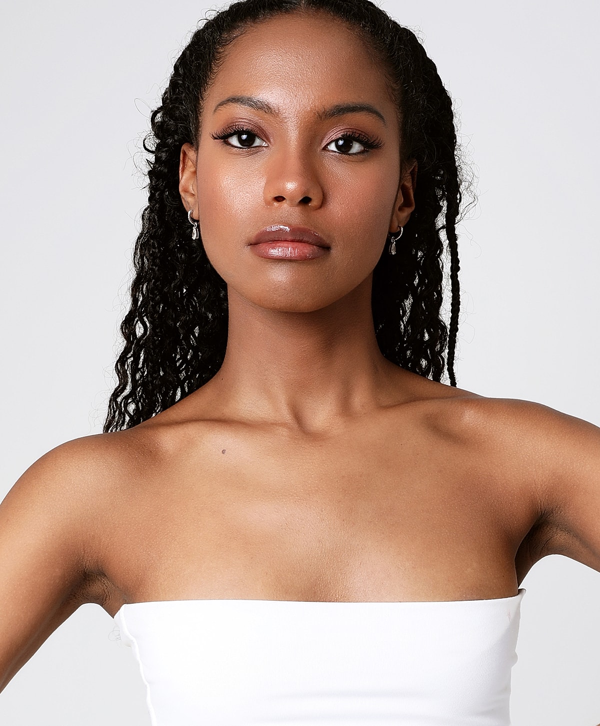 Model with curly hair in strapless top.